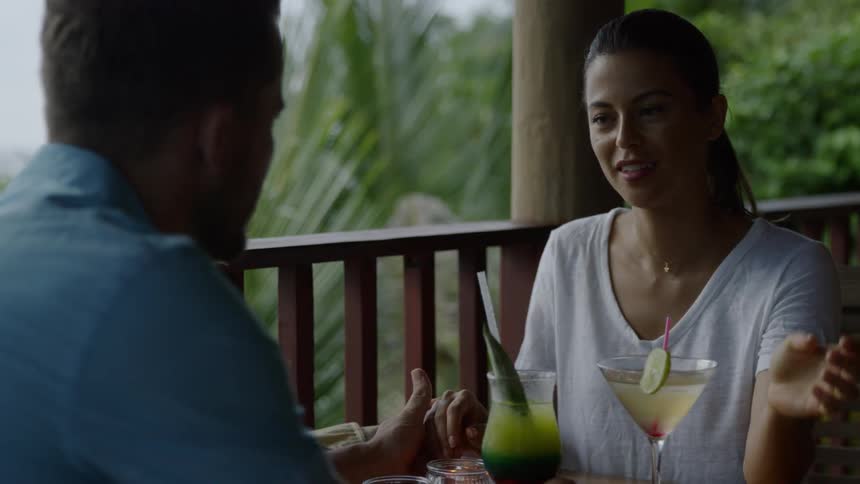 Man and woman having drinks at table outside on porch