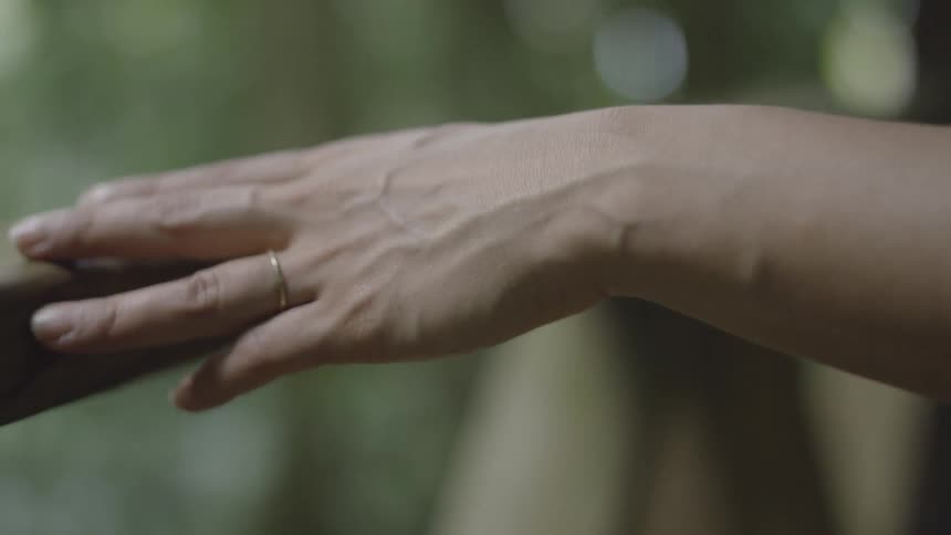 A person traces their hand across a railing