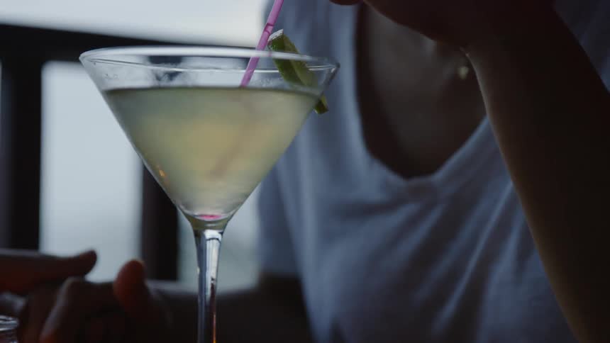 Woman stirs her drink with a pink straw