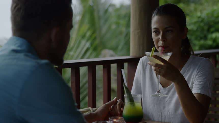 Man and woman sit at a table on a balcony drinking