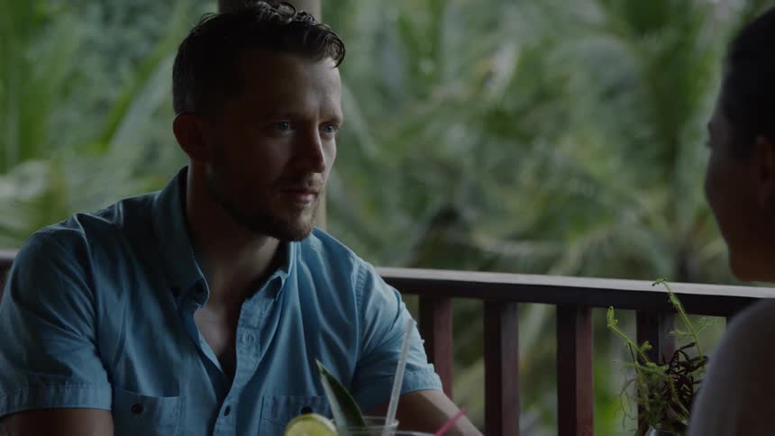 A man sitting out on a deck raises a tropical drink