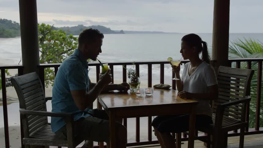 Man and woman sit at a table on a balcony drinking