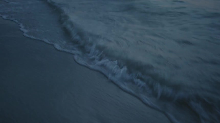 Water splashes up on sandy beach at night