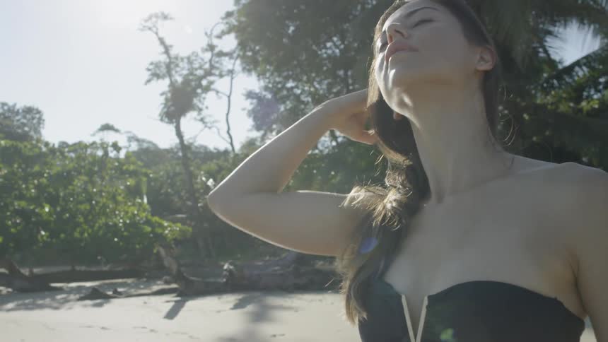 Woman pushes hair back and walks on a beach