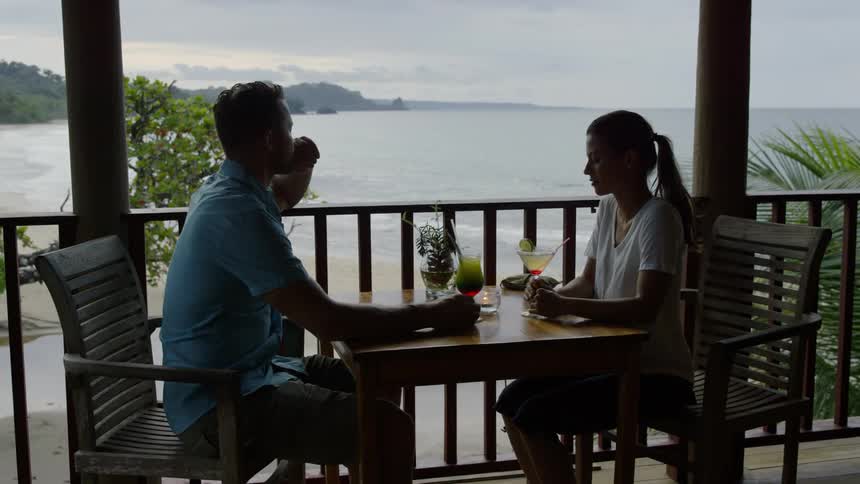 Man and woman sit at a table as they look out at a lake
