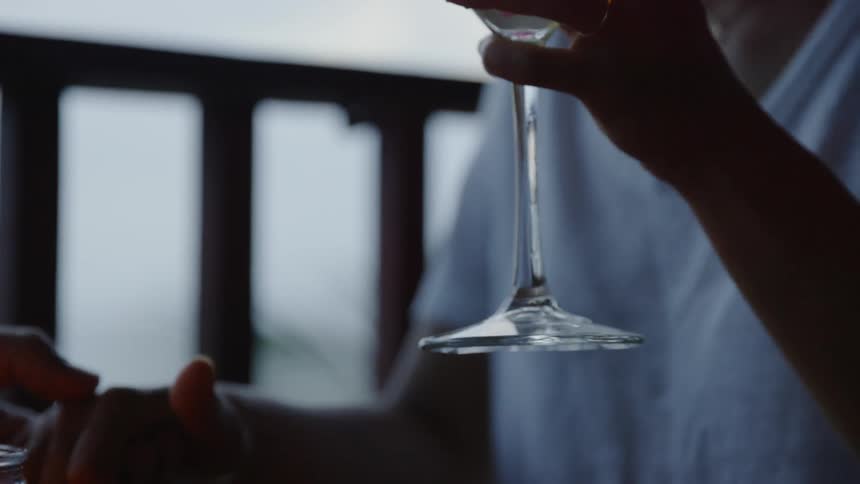 A woman holds a glass on the porch