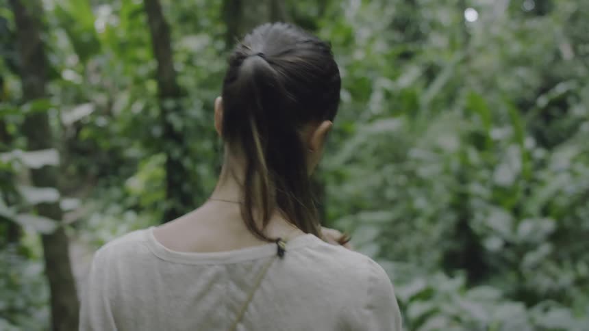 A woman turns around laughing as she hikes in the woods