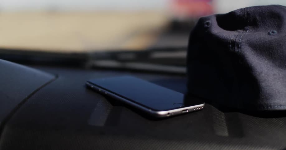 Vehicle dashboard with a hat and phone lying on top