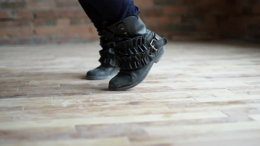 Someone in boots dances on a wood floor