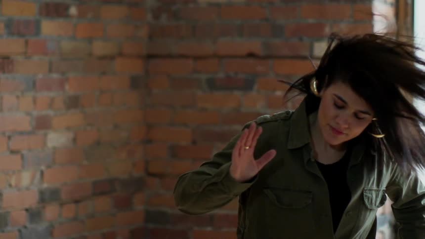 Woman dancing near a brick wall