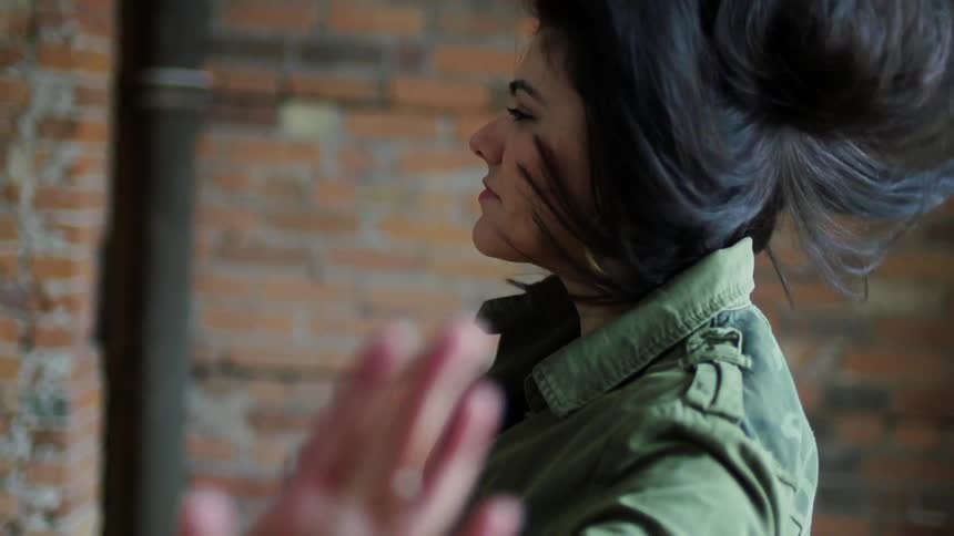 Woman dancing near a brick wall