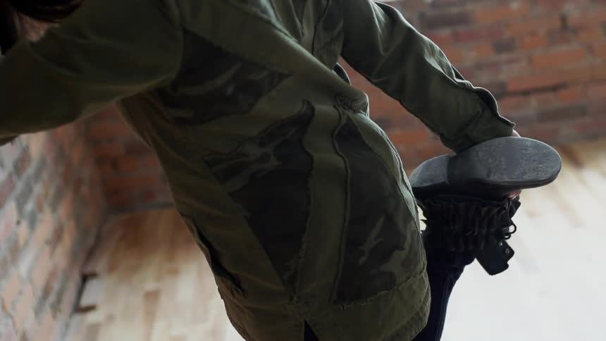 A person leaning against a brick wall and stretching their leg