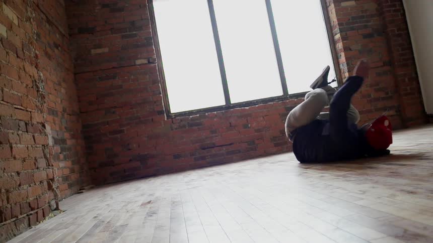 Man break dancing in an empty room with a window
