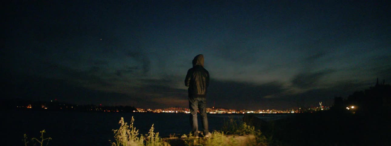 A person stands on the rock by the shore