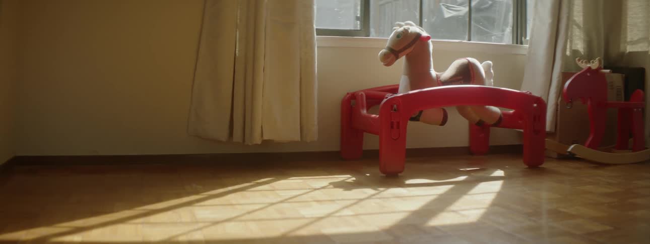 A rocking horse sits next to a window