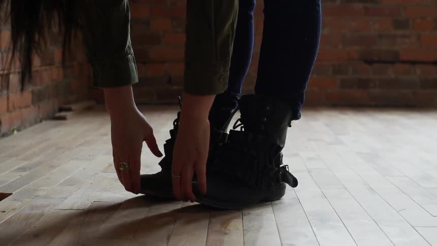 A woman is stretching her hands to her toes indoors