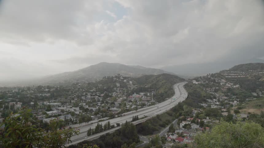 Traffic is flowing on a freeway in an urban valley on a stormy day