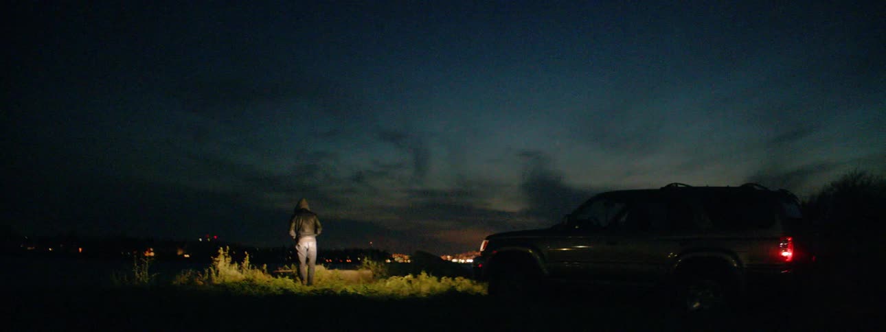A man walks in front of a trucks headlights