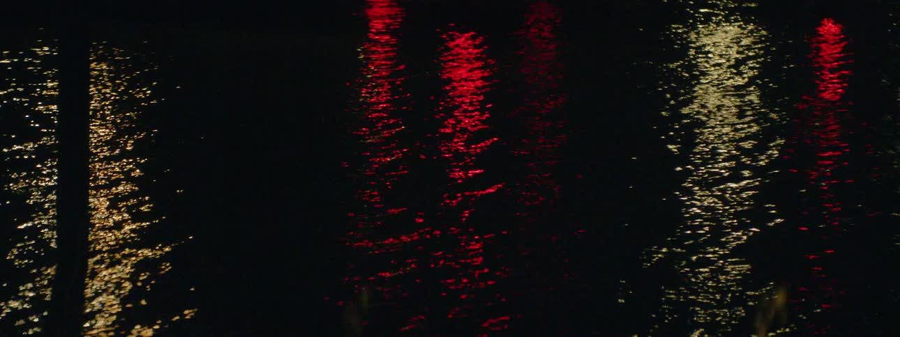 Light from the shore shimmers on the water surface at night