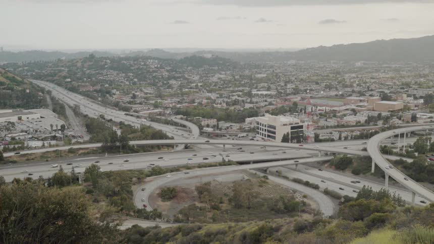 A freeway is flowing through a hilly community during a cloudy day
