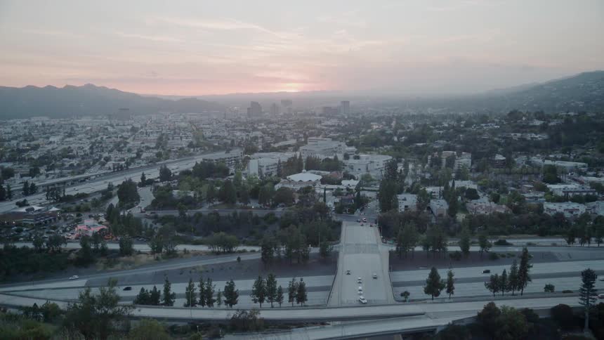 Traffic is flowing on a freeway system in the los angeles basin at sunset