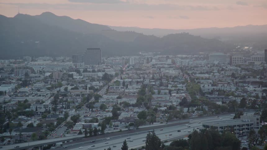 Traffic is flowing on a freeway system in valley community at sunset
