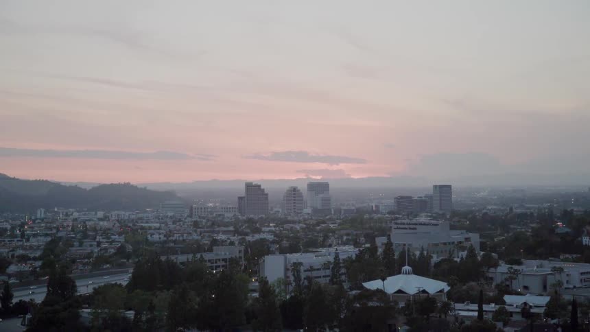 The sun is setting behind the buildings in the distance