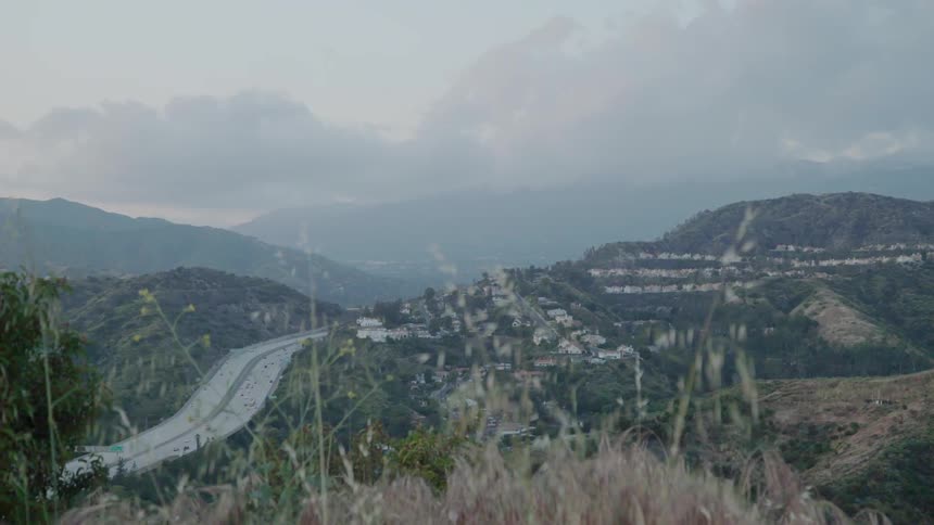The cars drive on the highway going over the hill