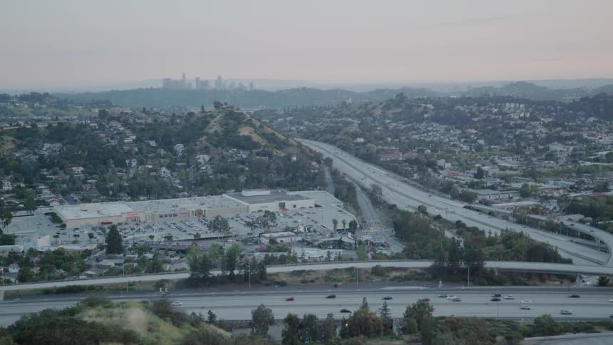 Traffic is flowing on a freeway system in the los angeles basin at sunset