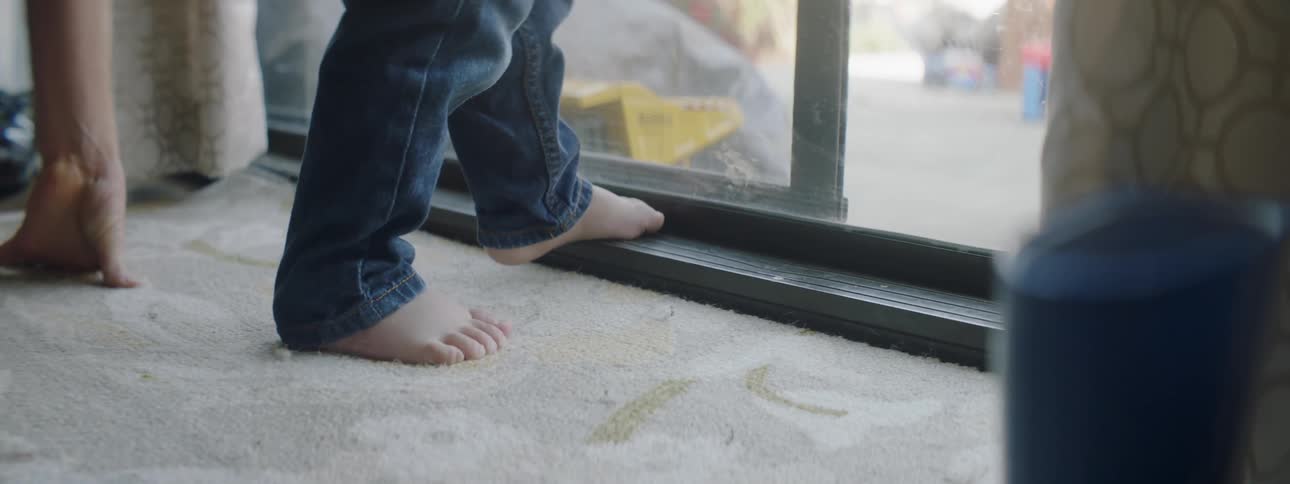 Young boy stands next to a sliding glass door
