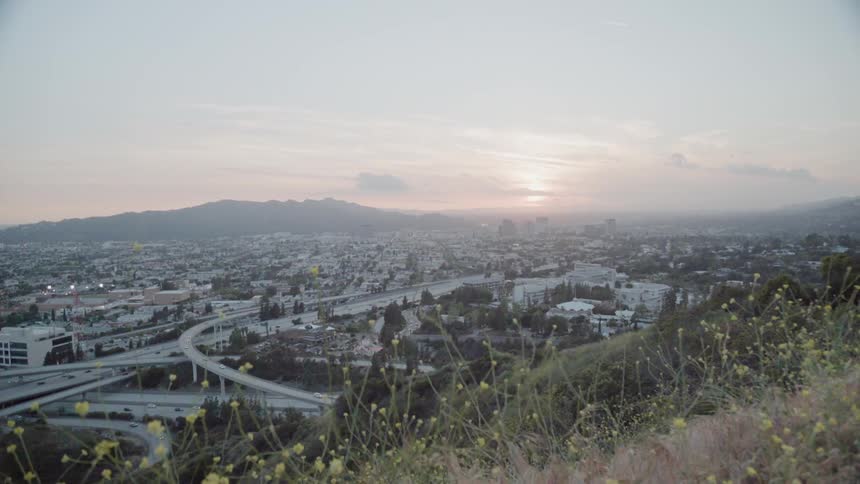 Over the green hill is a highway running through a city
