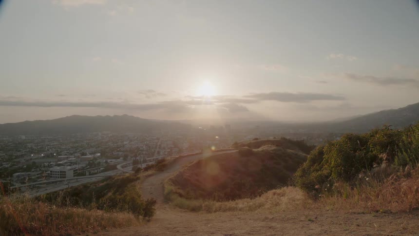 The sun is shining over a community in a valley at sunset