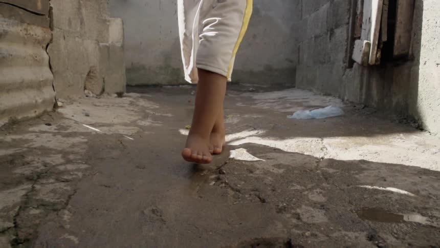 A person walking down an alleyway in gray shorts with a yellow stripe