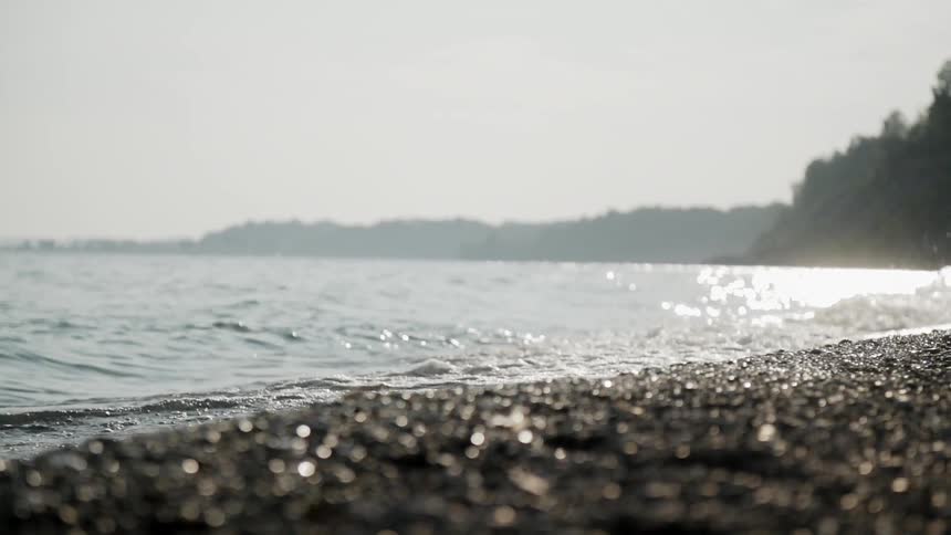 The tide flows onto the rocky beach shore