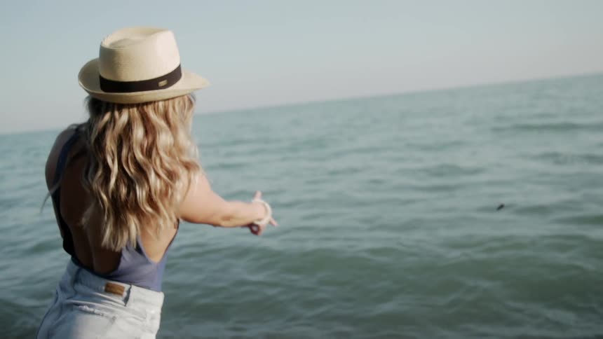 The woman skips a rock out on the water