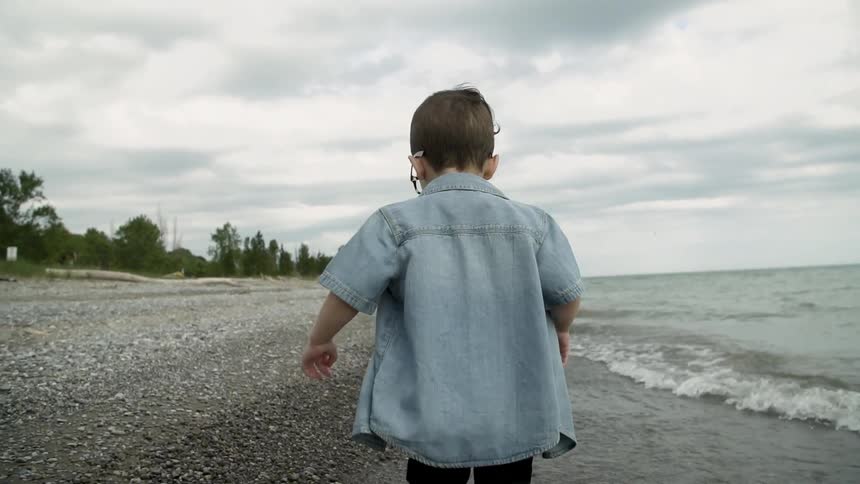 A little boy is running along the beach