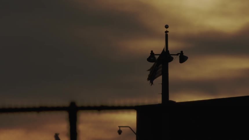 A u.s. flag is flapping in the breeze on top of a building at dusk