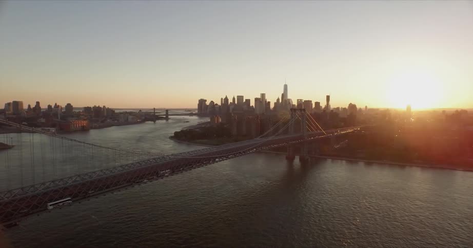 Traffic moves across a city bridge over a harbor at sunset