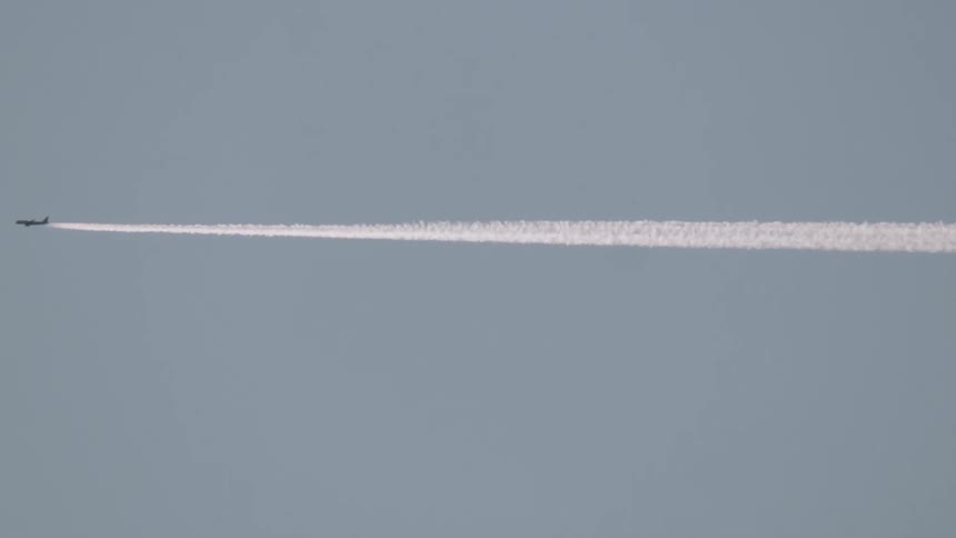 An airplane leaves a white trail as it flies across the sky