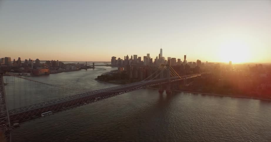 The sun sets over a city bridge and skyscrapers