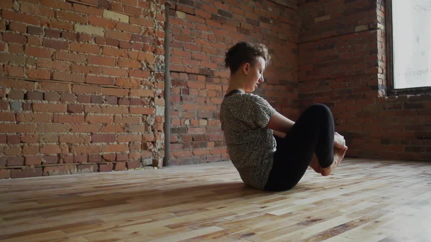 A woman is sitting on the floor stretching