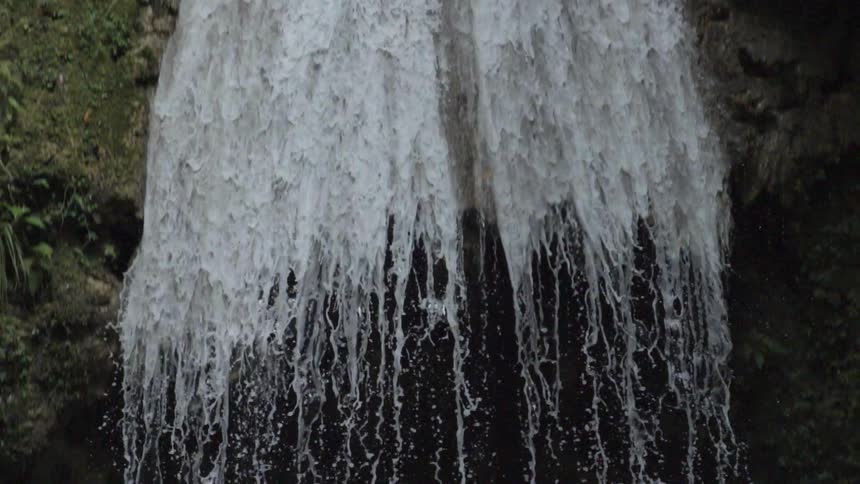 A waterfall cascading over rock into a body of water