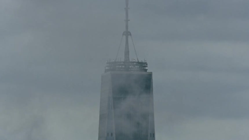 Clouds are drifting near the top of a skyscraper during the day