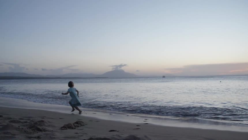 Child running along the water on a beach