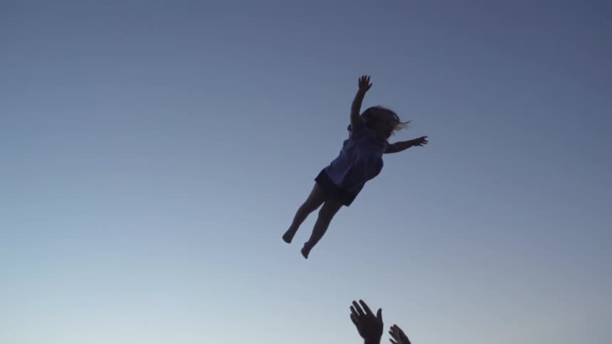 Man picks up and tosses child in the air on the beach