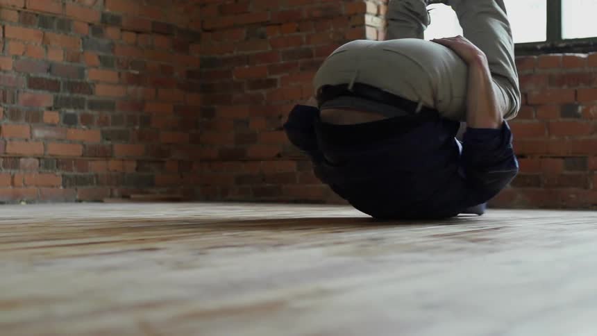 A man break dances on a wood floor