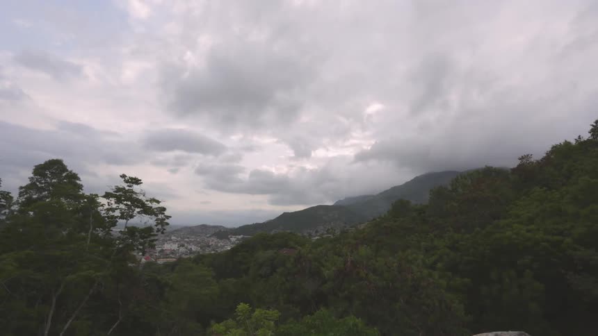 Time lapse of mountains and trees as large clouds pass overhead