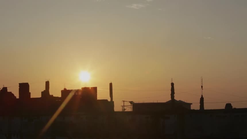 The sun sets behind some city buildings
