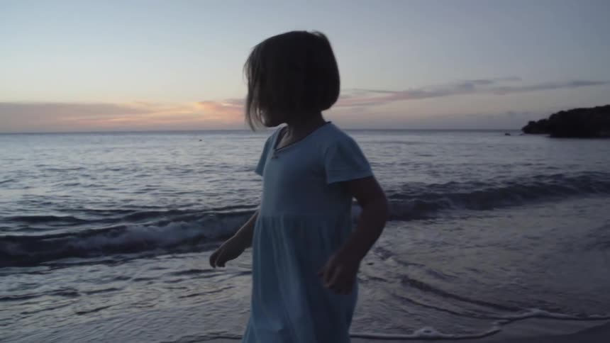 A girl running along the beach at sunset
