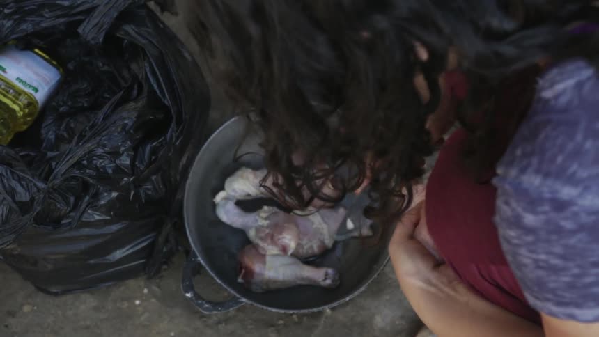 A woman cuts chicken legs over a pan